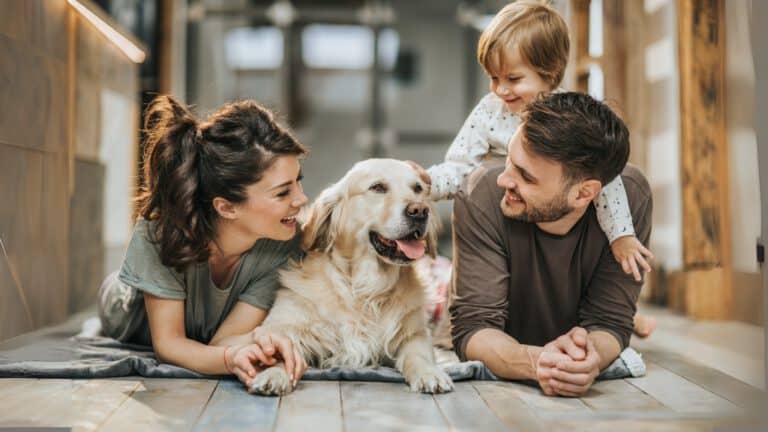 Familie mit Hund auf dem Boden, lachend und glücklich