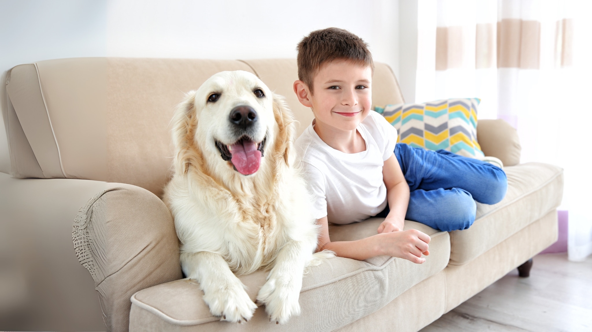 Mit der Hundekrankenversicherung gut geschützt - Kind mit Hund auf der Couch.