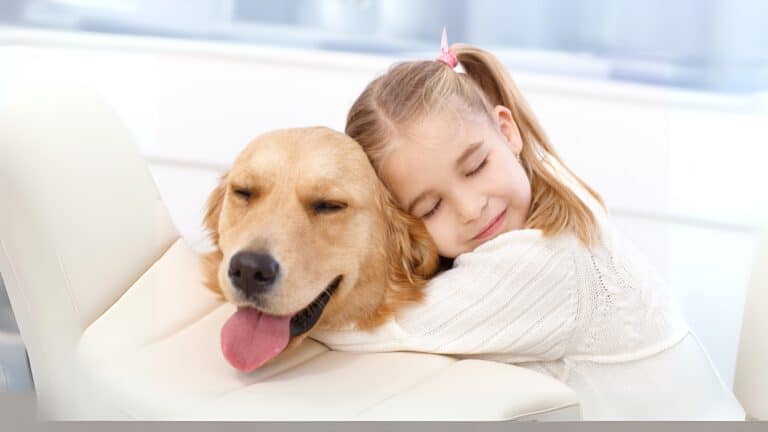 Kind umarmt Hund auf der Couch