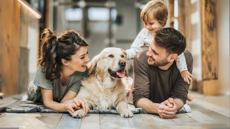 Junge Familie mit Hund auf dem Boden – HanseMerkur Hundeversicherung