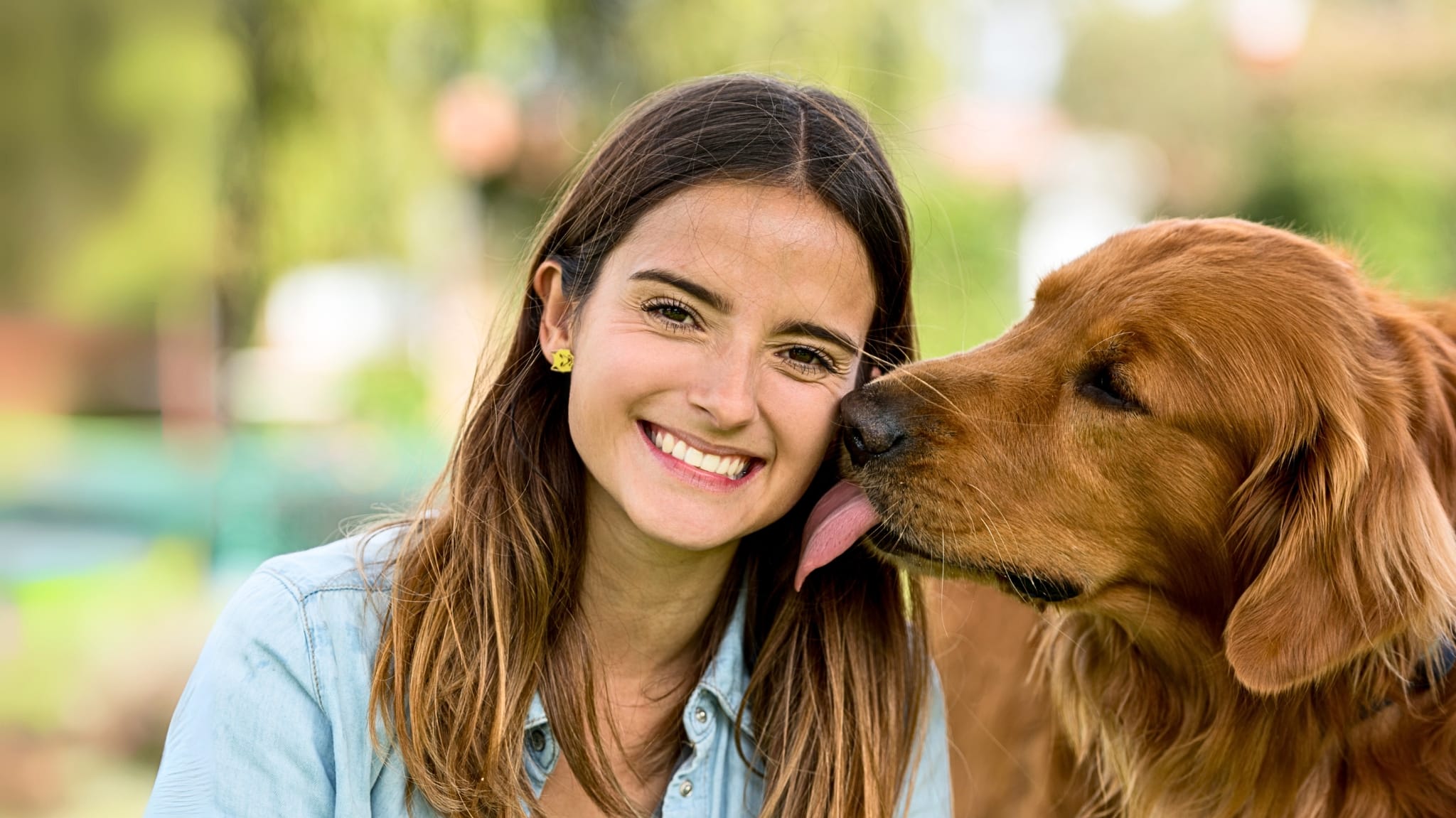 Hund leckt lachende Frau ab – Vorteile der HanseMerkur Hundeversicherung