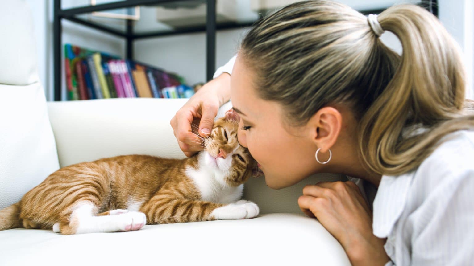 Geschützt durch HanseMerkur Katzenversicherung - Frau kuschelt mit schnurrender Katze – HanseMerkur Katzenversicherung