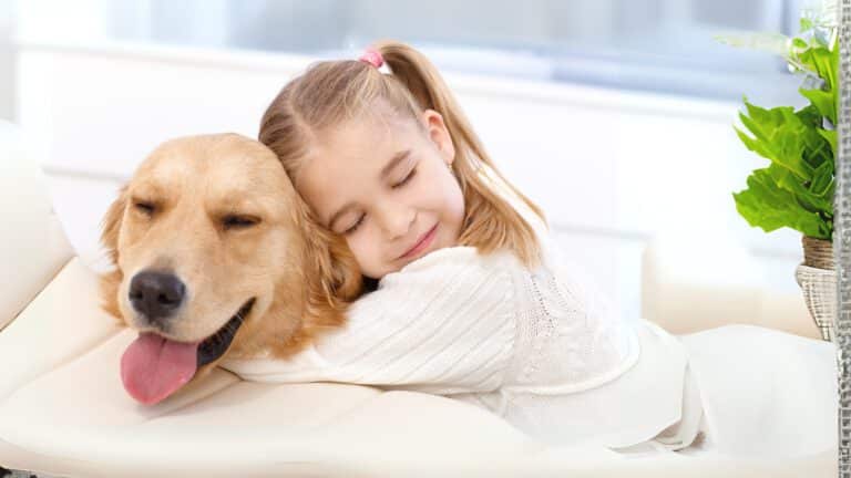 Kind hält Hund liebevoll umschlungen, beide entspannt und glücklich.