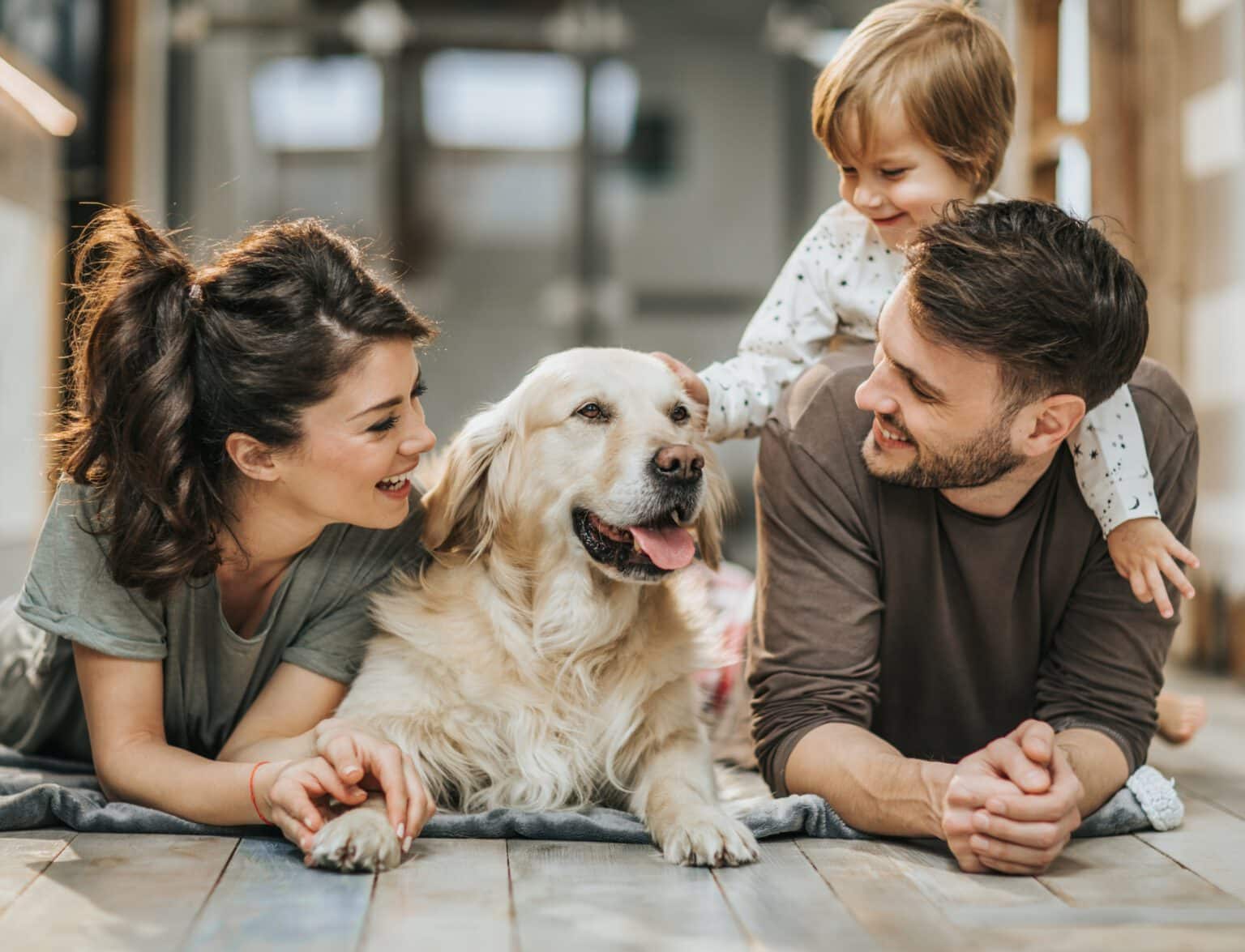 Geschützt durch die Hundeversicherung - Familie und Hund glücklich auf dem Fußboden.